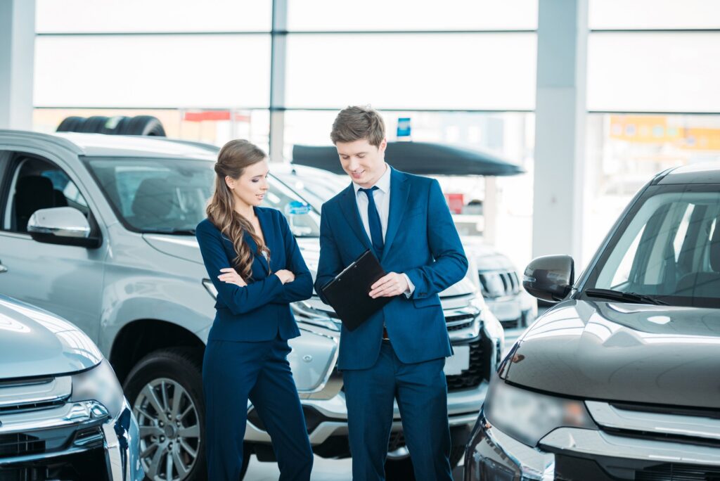 Sales managers of a car showroom standing and looking at clipboard